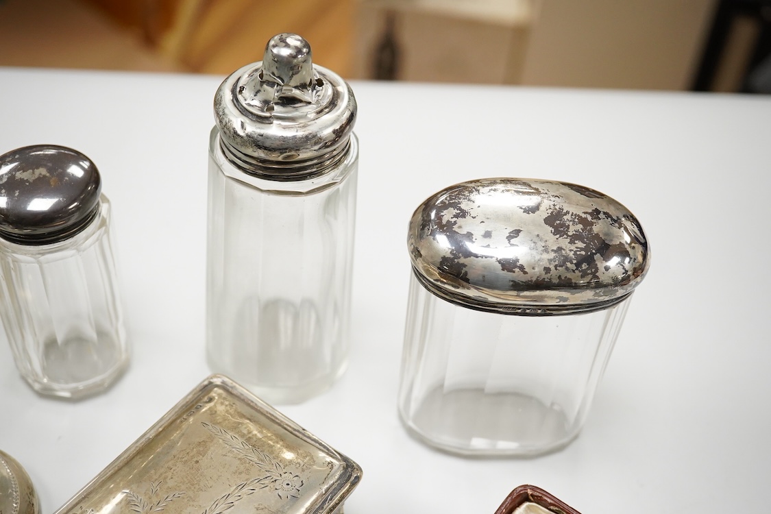 An early 20th century silver mounted cut glass scent bottle, five silver mounted glass toilet jars, a pair of silver mounted dwarf candlesticks, two silver condiments, a sterling jug(weighted), a sterling cup and cover(w